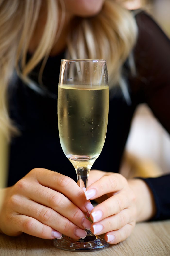 Close-up of a woman's hands holding a glass of champagne indoors.