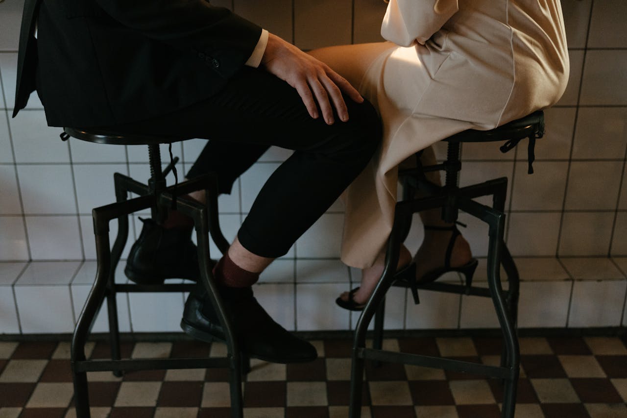 Close-up of a couple sitting intimately at a bar, dressed elegantly, evoking romance.